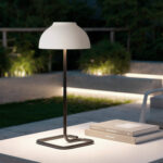 Lampe à poser blanche avec abat-jour hémisphérique, pied métallique noir et base rectangulaire, pour extérieur