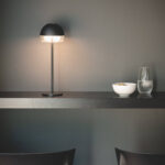 Lampe à poser noire, abat-jour demi-sphère, tige fine et base plate, éclairage doux et diffus