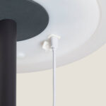 Lampe à poser, vue dessous: abat-jour rond blanc, tige noire aluminium et câble blanc avec connecteur