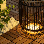 Lampe à poser noire en métal style lanterne, lumière chaude, posée sur terrasse en bois