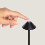 Lampe extérieure noire en métal, abat-jour conique et tige fine, bouton de commande circulaire au sommet