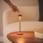 Lampe à poser métal couleur terre cuite mate, tige fine et abat-jour conique sur table