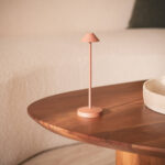 Lampe à poser terre cuite en métal mat, tige fine et abat-jour conique, base ronde sur table en bois