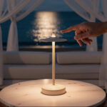 Lampe à poser beige en métal, plateau circulaire, lumière douce, posée sur table extérieure