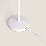 Lampe à poser blanche base ronde avec tige verticale et câble de recharge branché