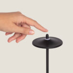 Lampe à poser noire en métal, abat-jour disque, tige fine et bouton tactile sur le dessus