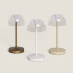 Trois lampes à poser LED avec abat-jour transparent et piètement métal beige, blanc et laiton