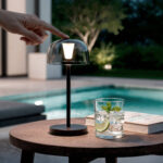 Lampe à poser LED métal noir avec abat-jour dôme fumé sur table extérieure