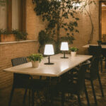 Lampe à poser noire avec diffuseur blanc et pied métallique, posée sur table extérieure