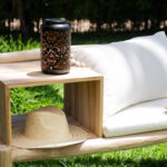 Lampe à poser cylindrique en métal ajouré noir, style lanterne, posée sur tablette de bois extérieure