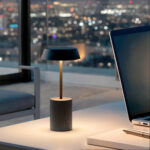 Lampe à poser LED noire, base cylindrique sombre, tige métal doré et abat-jour plat diffusant lumière chaude