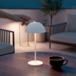 Lampe à poser blanche compacte avec abat-jour demi-sphérique, tige fine et base ronde, usage extérieur