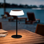 Lampe à poser solaire en métal noir, abat-jour blanc translucide, piètement rond et cordon de tirage