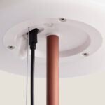 Lampe à poser solaire mât métal brun cuivré, base d'embase blanche ronde et câbles visibles