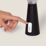 Lampe à poser noire conique avec interrupteur blanc près de la base