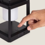 Lampe à poser solaire LED noire en métal, structure rectangulaire, diffuseur blanc et bouton d'allumage sur la base