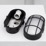 Plafonnier extérieur ovale noir avec grille métallique et diffuseur opalin, support d'ampoule visible