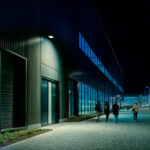 Projecteur LED mural noir éclairant en blanc froid, design plat pour façade extérieure et chemin piéton