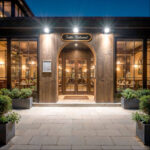 Projecteur LED mural noir éclairant l'entrée extérieure, faisceau dirigé vers le sol