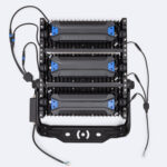 Projecteur LED extérieur noir à trois modules, boîtier métallique, support de fixation et câbles de connexion visibles