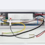 Réglette LED ouverte, boîtier blanc, ballast électronique et câblage multicolore visibles, profil rectangulaire