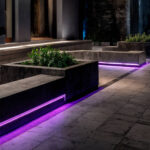 Ruban LED extérieur violet encastré sous murets en béton pour éclairage de bordure