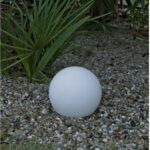 Lampe sphérique extérieure blanche posée sur gravier