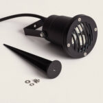 Spot extérieur sur piquet noir, corps cylindrique métallique avec grille avant et câble