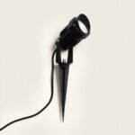 Spot extérieur sur piquet noir, boîtier cylindrique, finition mate, câble d'alimentation visible