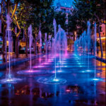 Spot LED encastré au sol illuminant jets d'eau en bleu et magenta