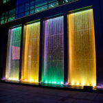 Spot LED RGB encastré au sol multicolore éclairant un rideau d'eau