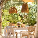 Suspension extérieure en fibres naturelles couleur sable, abat-jour frangé rond suspendu au-dessus d'une table de jardin