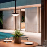 Suspension extérieure ronde noire à diffuseur blanc, design plat suspendue au-dessus d'une table de jardin