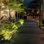 Projecteur linéaire encastré au sol éclairant façade et végétation en lumière chaude