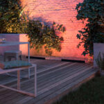 Projecteur linéaire au sol, boîtier noir, éclairage amarante lavant la façade de brique