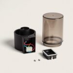 Applique murale démontée, base noire, diffuseur cylindrique fumé transparent et platine de fixation avec vis