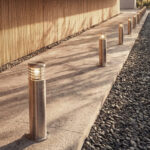 Balise sur pied en acier inoxydable cylindrique, fixation au sol apparente, diffuseur lumineux supérieur