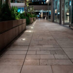 Spot encastrable au sol rond en inox, éclairage blanc chaud, installation linéaire le long d'une allée pavée